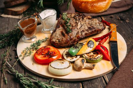 Side view on juicy beef steak with grilled vegetables on the wooden board, horizontalの写真素材