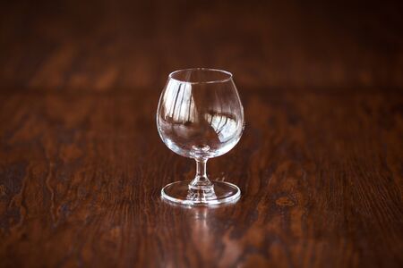 Empty elegant cognac glass on the dark wooden table, horizontalの写真素材
