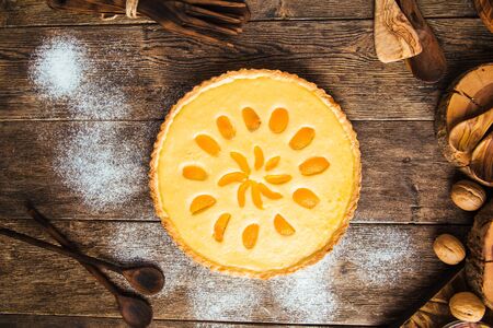 Top view on sweet delicious apricot curd cake pie with powdered sugar on the wooden table, verticalの写真素材