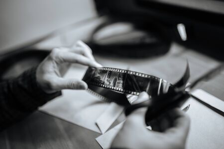 A man examines a black and white retro 35mm film. Holds in hands. Horizontalの写真素材