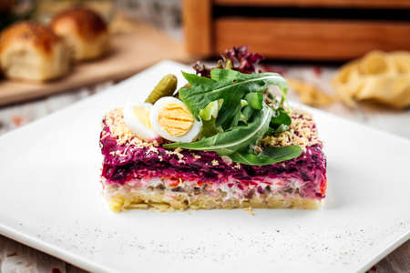 Russian dish herring under a fur coat with greens on a light background, horizontalの写真素材