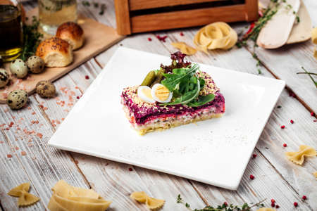 Russian dish herring under a fur coat with greens on a light background, horizontalの写真素材
