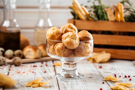 Small sweet dessert profiteroles in a glass on the wooden table, horizontalの写真素材