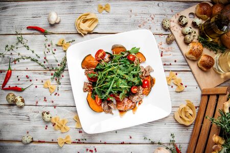Top view on gourmet warm salad with baked pumpkin spinach and beef tenderloin, horizontalの写真素材