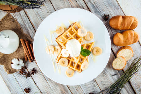 Top view on belgian waffles poured with ice cream and banana syrup, horizontalの写真素材