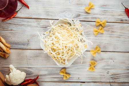 Top view on fiber smoked cheese chechil in a bowl on the white wooden table, horizontal
