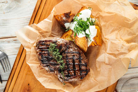 Top view on beef steak with baked potatoes with sour cream and pepper sauce, horizontalの写真素材
