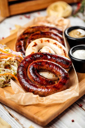 Closeup on grilled sausages with sauerkraut and sauces, horizontal