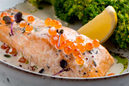 Closeup on festive dish salmon with roe lemon and broccoli in creamy sauce