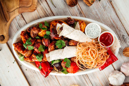 Top view on big grilled shashluq platter set with different meat marinated onion and sauce