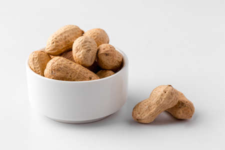 Closeup on isolated peanut nuts in a bowl on the white background