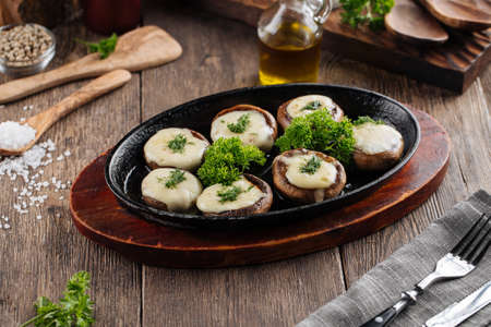 Baked stuffed champignon hats in a pan on the wooden tableの写真素材