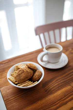Selective focus on cookies with morning coffee in a white cup on the wooden tableの写真素材