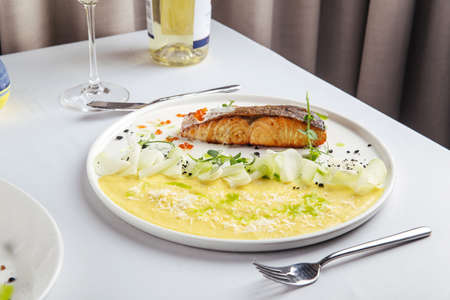 Fried salmon with mashed potatoes and red caviar on a white plate