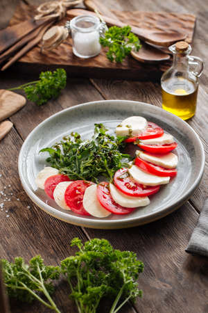 Classic italian caprese salad on the wooden table, verticalの写真素材