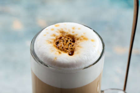 Closeup on foamed latte coffe in a glass with a blurry background