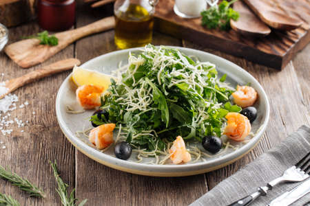 Fresh arugula salad with shrimps and olives on the wooden tableの写真素材