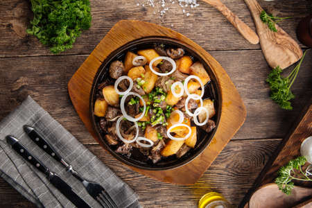 Top view on rustic roasted potatoes and beef in a pan on the wooden boardの写真素材