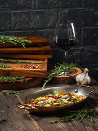 Side view on a delicious dish seabass fillet with mushrooms and potatoes in a pan on a wooden tableの写真素材