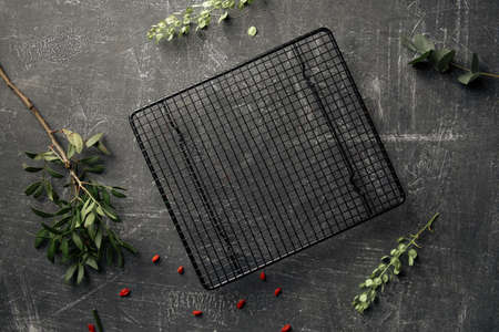 Top view on the decorated grey concrete background with black grid cake trayの写真素材