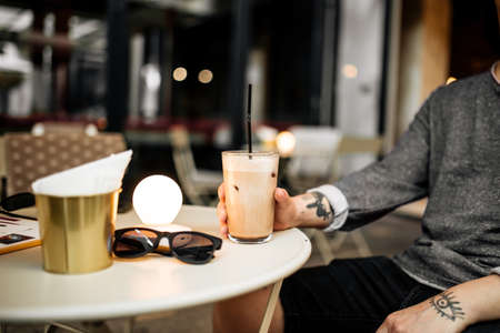 Man drinking latte coffee sitting on the summer terrace in cafeの写真素材