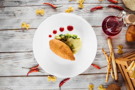 Top view on restaurant served chicken Kiev cutlet with mashed potato and lingonberry sauce