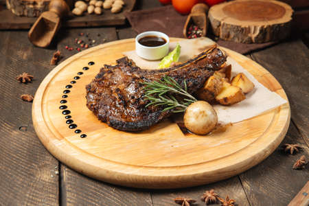Side view on cowboy beef steak on a wooden board with potatoesの写真素材