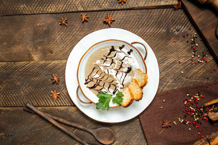Top view on gourmet mushroom cream soup with toasts in a bowl on the wooden decorated tableの写真素材