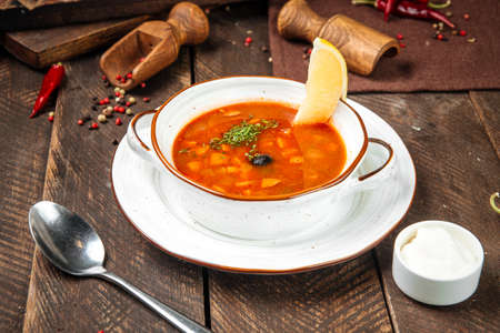 Side view on russian soup solyanka with smoked meats on the wooden tableの写真素材