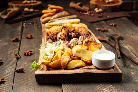 Fried salty beer snacks on the wooden board with saucesの写真素材