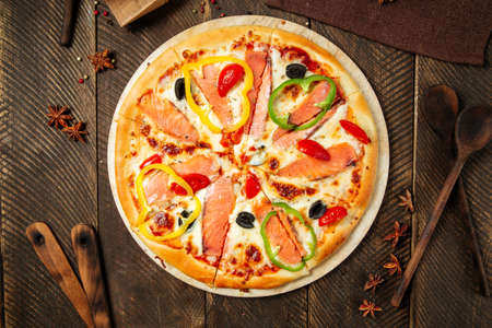 Top view on pizza with salmon and bell pepper on the wooden tableの写真素材