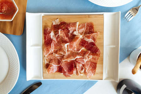 Top view on spanish sliced pork jamon on the white plateの写真素材
