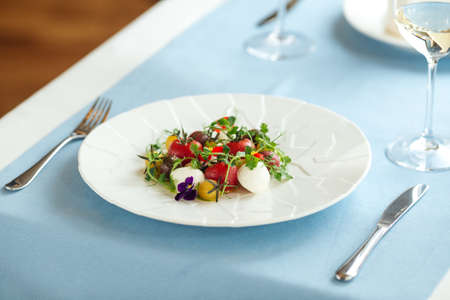 Closeup on fresh tomato salad with herbs on the blue served table