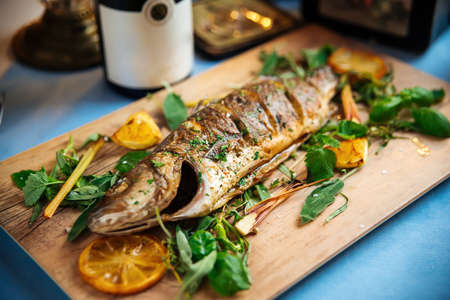 Closeup on roasted sea bass with herbs on the wooden board