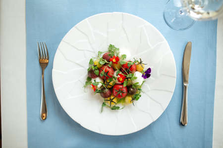 Top view on spanish peeled tomato salad with herbs on the blue served tableの写真素材