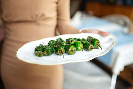 Waitress holding grilled spanish green padron peppersの写真素材