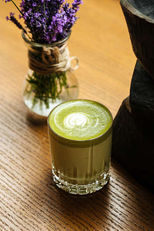 Closeup on green matcha beverage in a glass on the wooden table