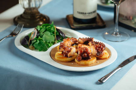 Side view on spanish national dish octopus in galician with greens salad