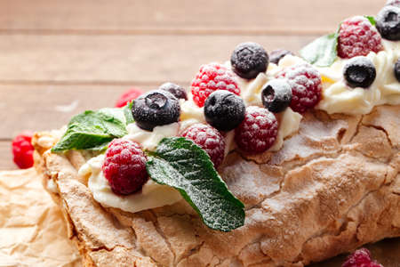 Closeup on meringue roll with berries sprinkled with powdered sugarの写真素材