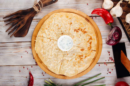 Top view on caucasian traditional thin  flatbread khychin with sour cream sauce on the wooden table