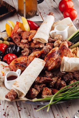 Closeup on assorted caucasian grilled meat shashlyq platter on the light wooden table