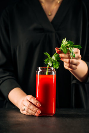 Woman making bloody mary cocktail with celeryの写真素材