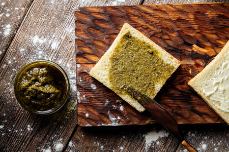 Spreading white bread slice with pesto sauceの写真素材