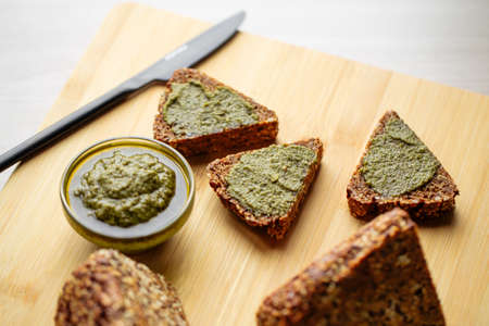 Sliced diet grain bread spread with pesto sauceの写真素材