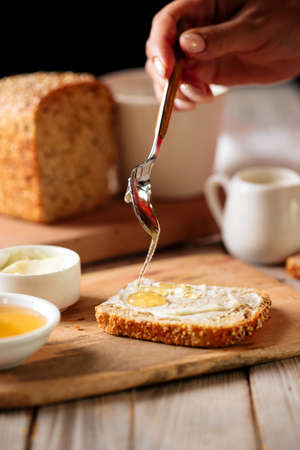 Side view on spreading bread slice with honeyの写真素材