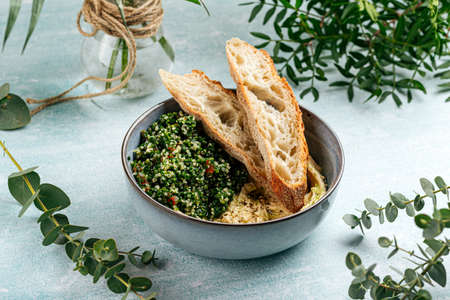 Bowl of hummus with tabbouleh salad and toastsの写真素材