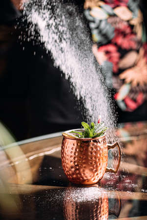 Bartender making cocktail in copper mug with sugarの写真素材