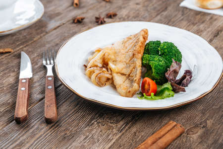Fried fish fillet with fresh vegetables on a table