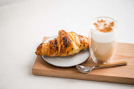 Glass of coffee latte with cinnamon and croissantの写真素材
