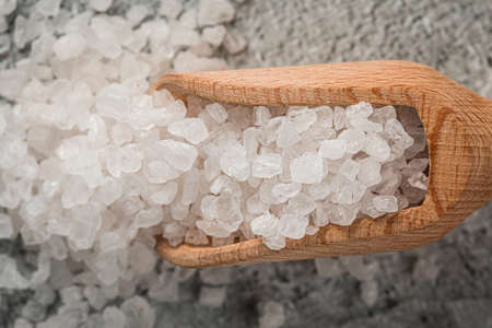 Heap of white salt in a wooden scoop